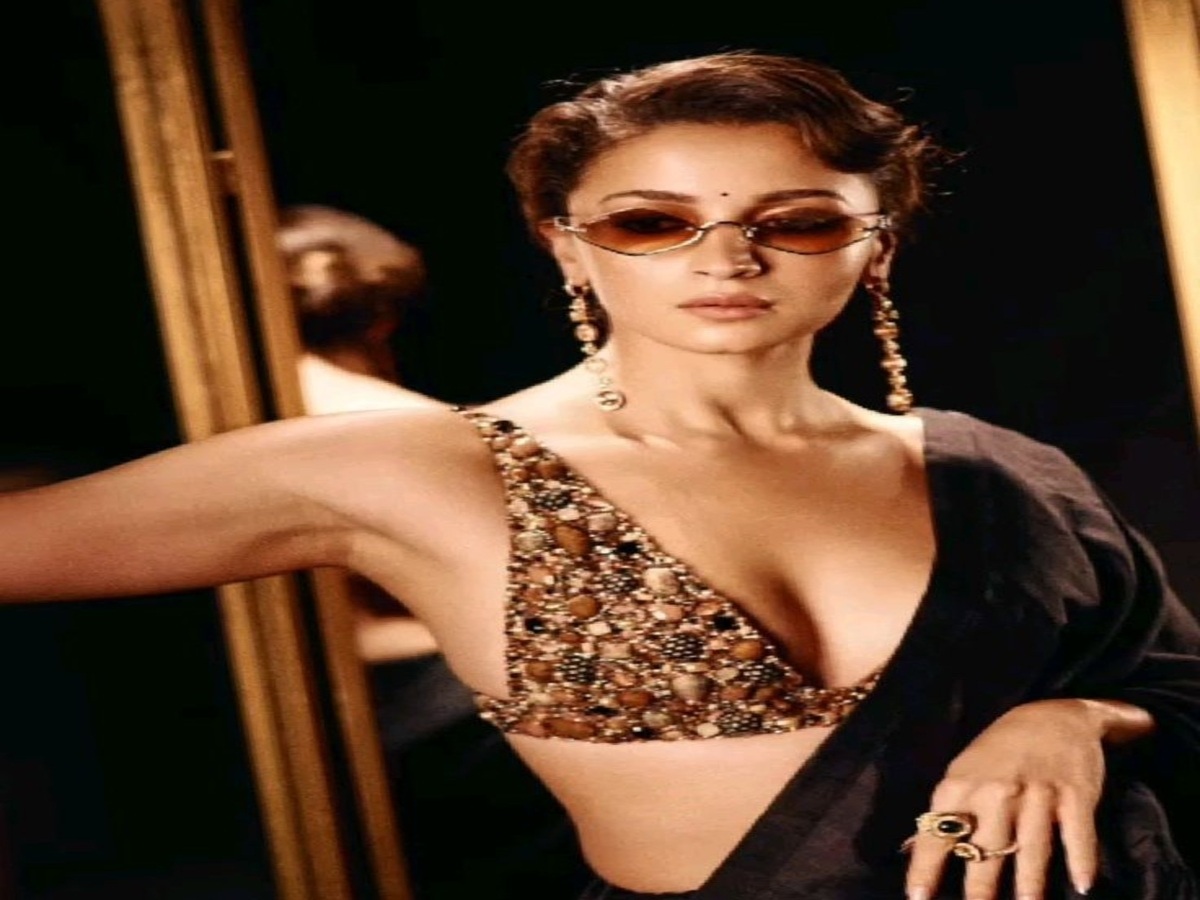 Alia Bhatt looking glamorous in an embellished outfit, posing elegantly in front of a reflective backdrop.