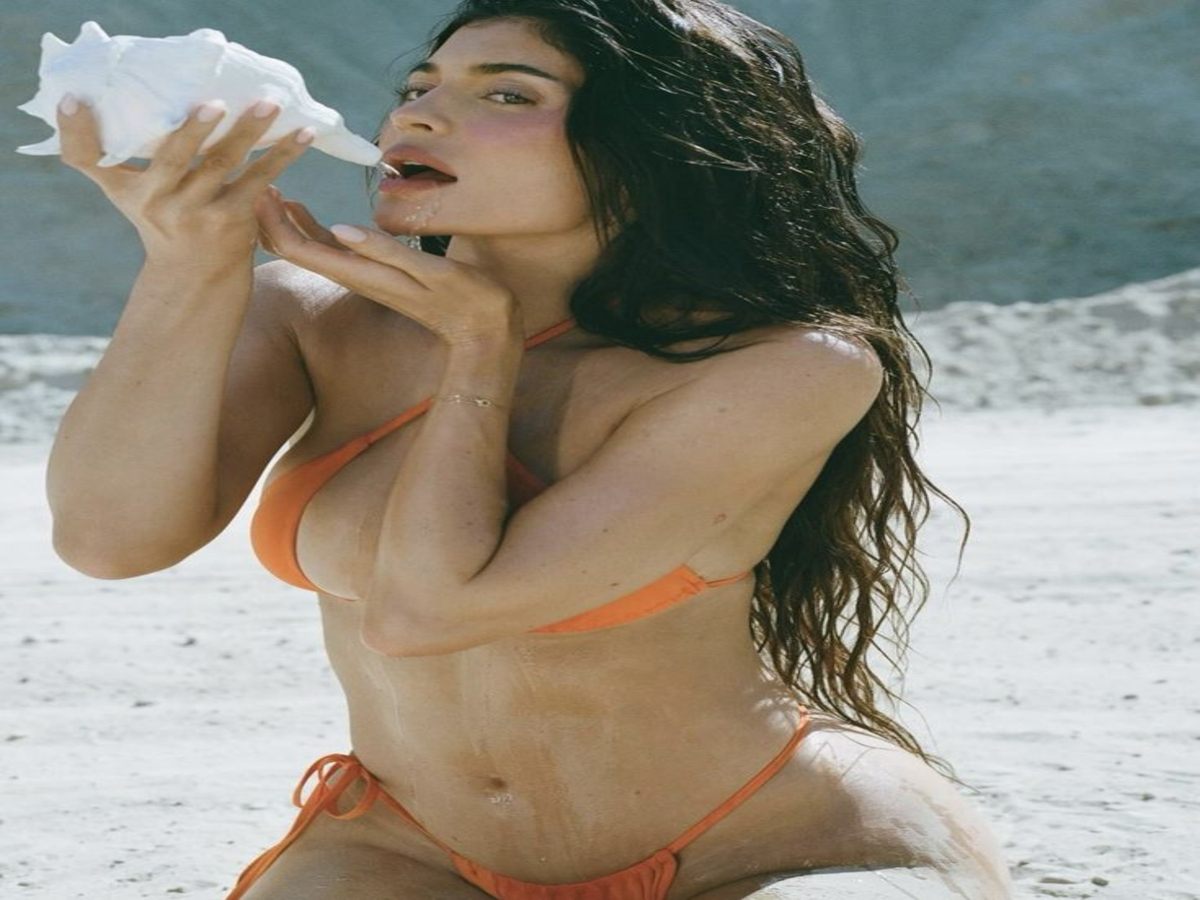A figure enjoying a sunny day at the beach in a bright orange bikini