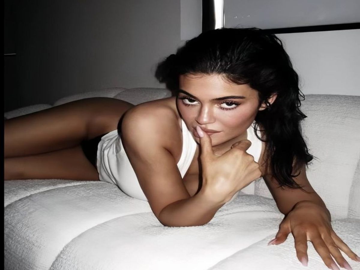 A stylish individual lounging in a cozy setting wearing a chic white top