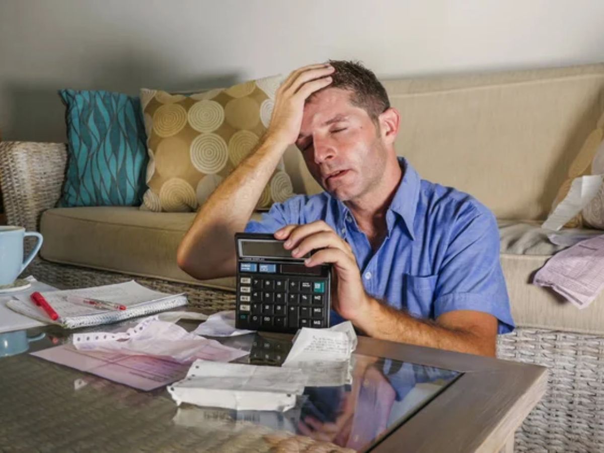 man confused while looking at a bill or financial document.