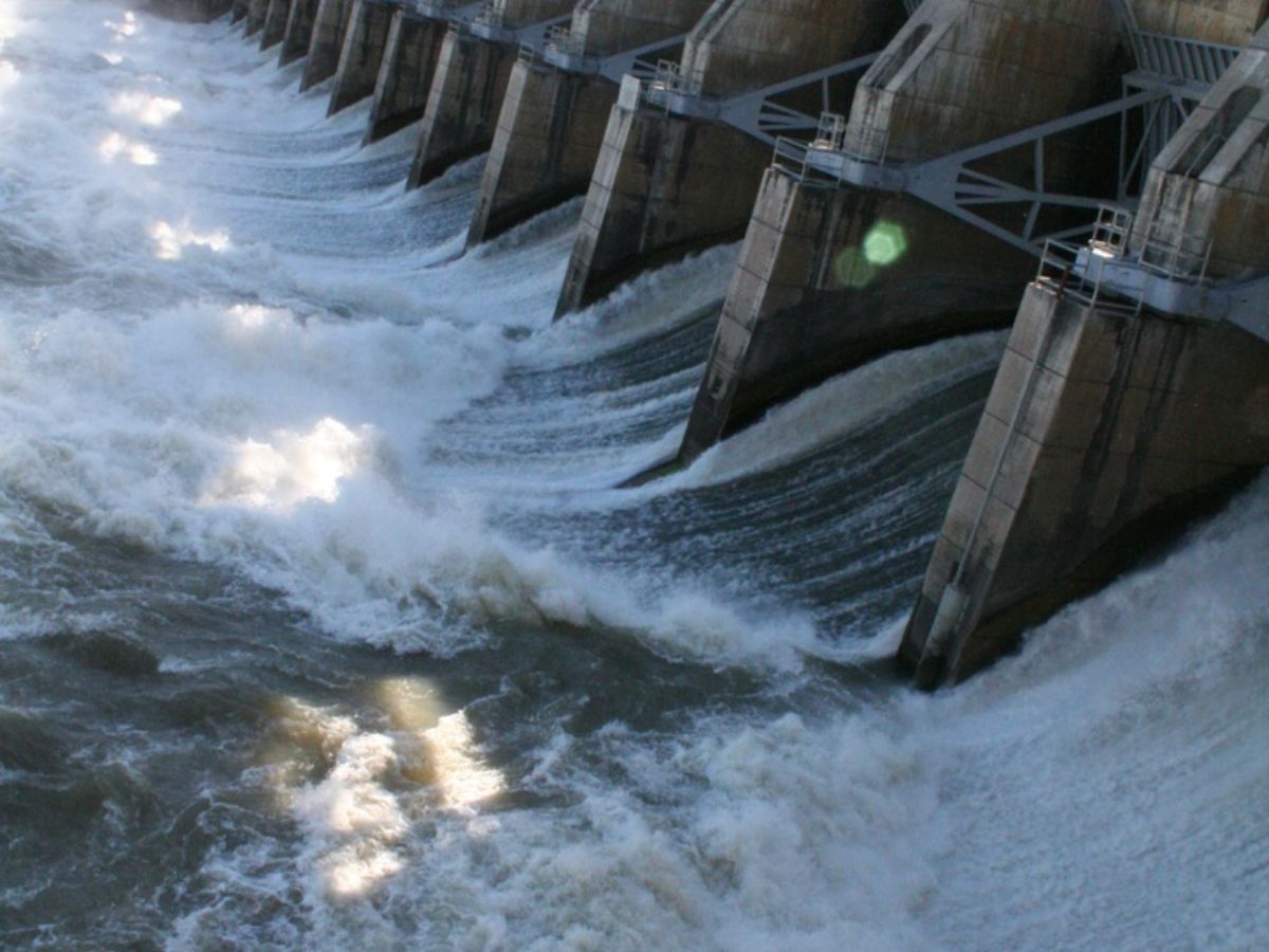 Overflowing Texas dam with foam and fallen trees during floods.