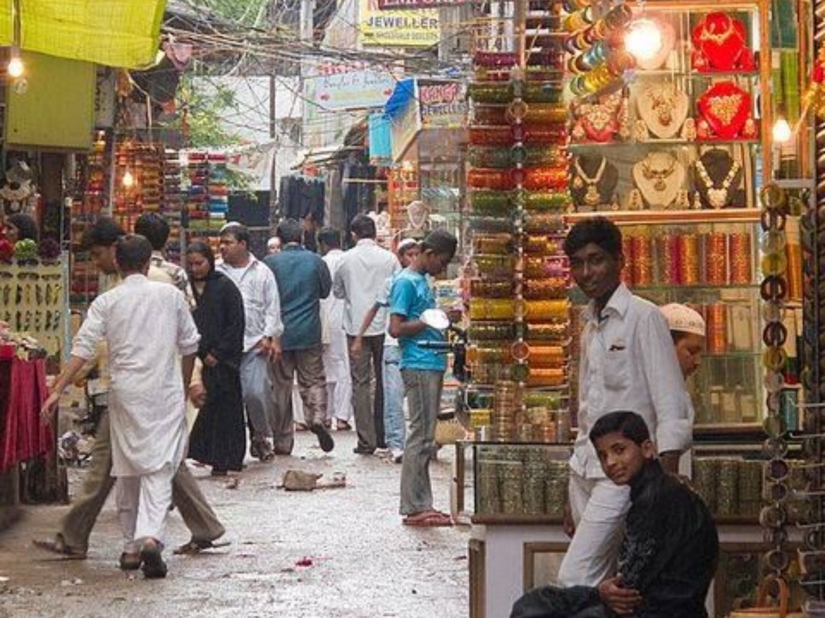 Narrow street in Chowk lined with old shops, rickshaws, and busy locals.