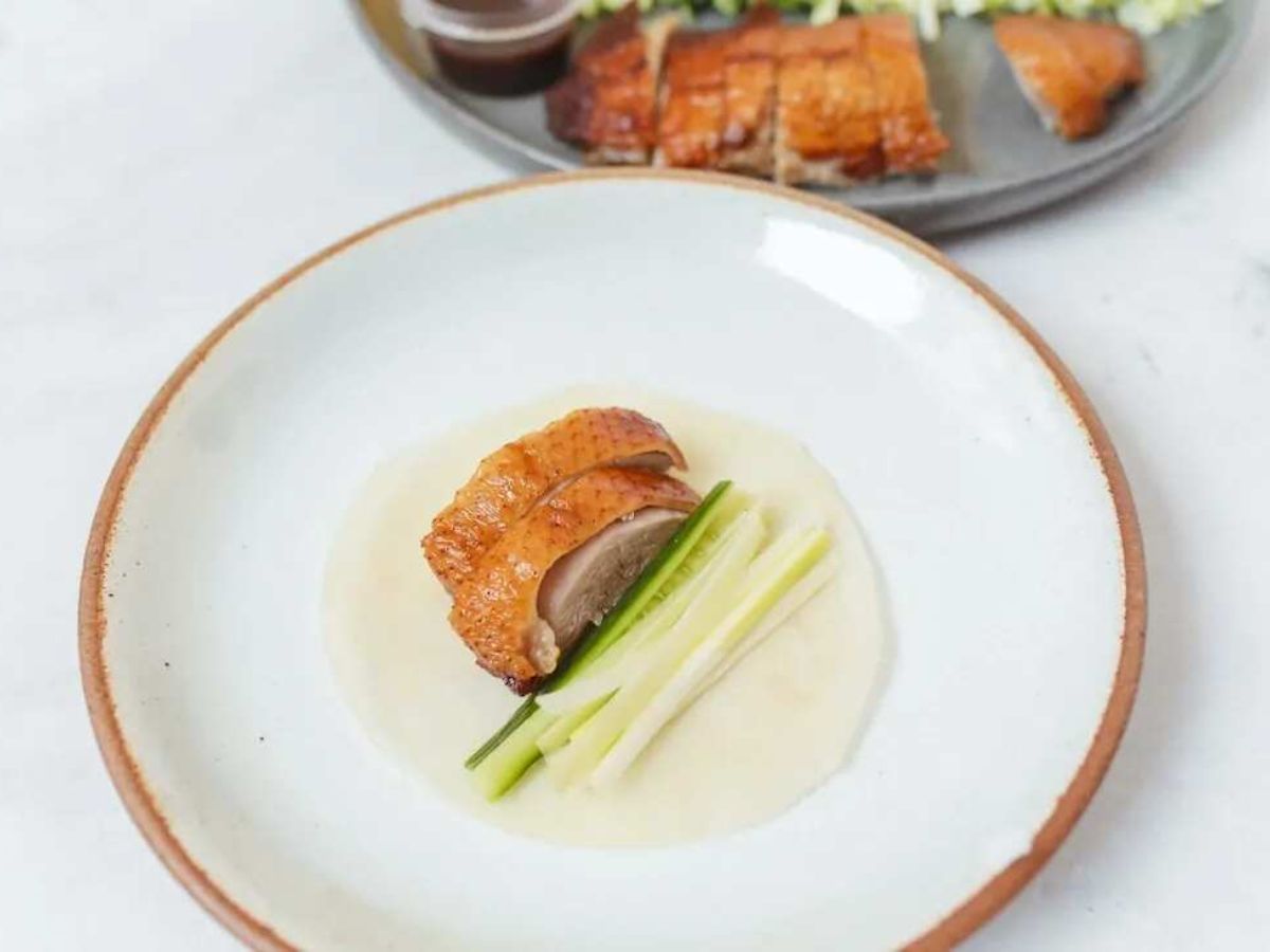 Sliced Peking duck on a pancake with cucumber and spring onion strips