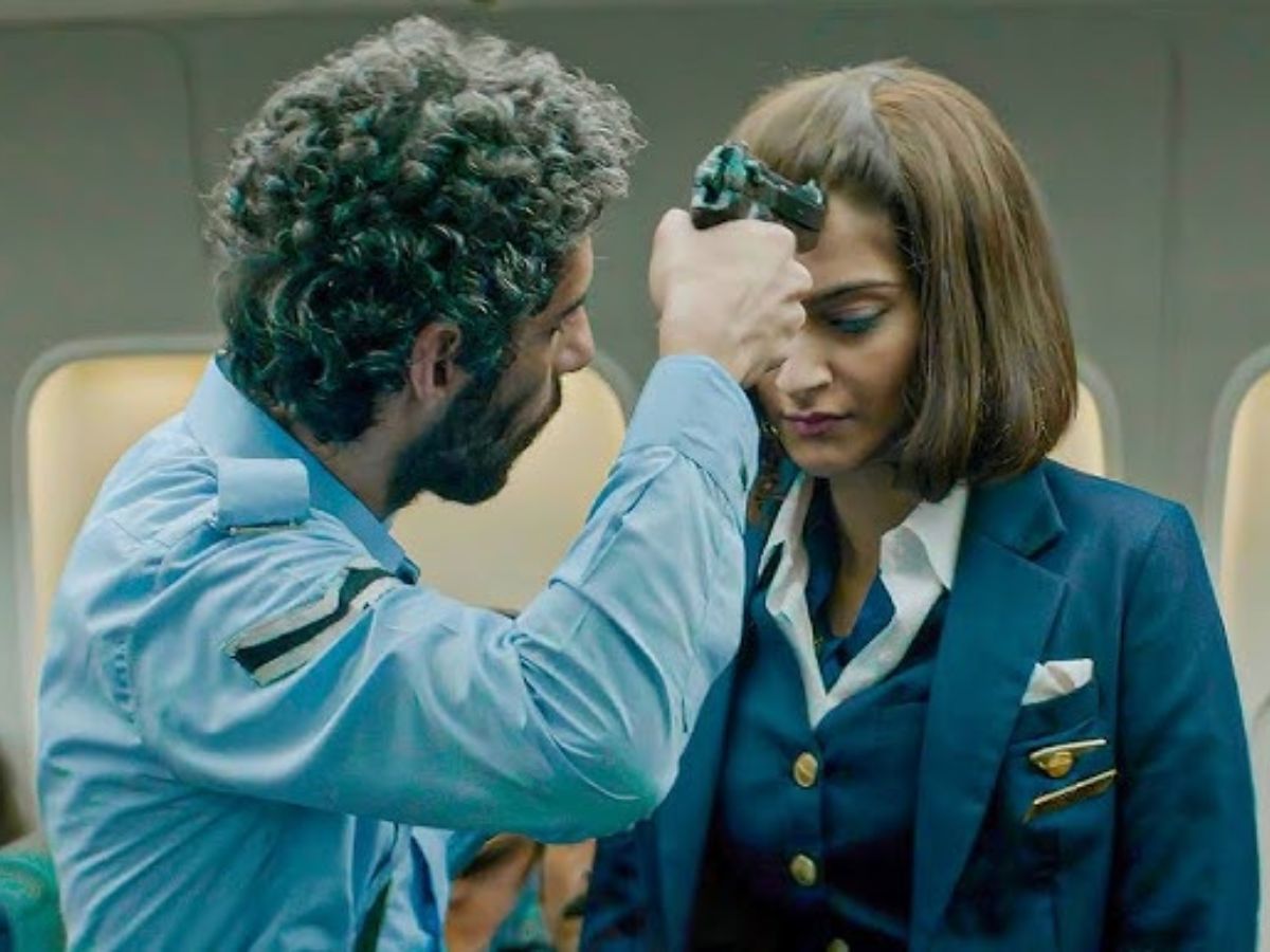 Sonam Kapoor as flight attendant Neerja Bhanot facing a tense moment during a hijack, with a hijacker pointing a gun to her forehead inside an airplane, from the film Neerja.
