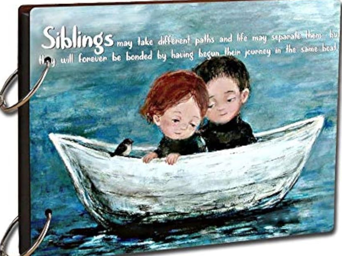 A wooden-bound photo album featuring a painting of two siblings in a boat and a sentimental quote about the bond between siblings.