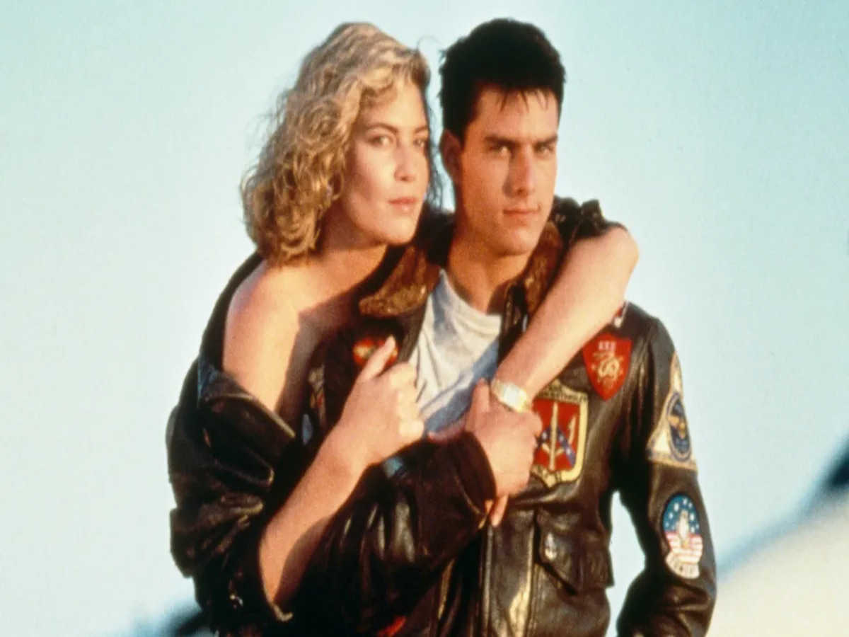 Tom Cruise kissing Kelly McGillis in "Top Gun," capturing a spontaneous moment that arose from an improvised action when Cruise forgot his lines, enhancing the emotional impact of the scene.
