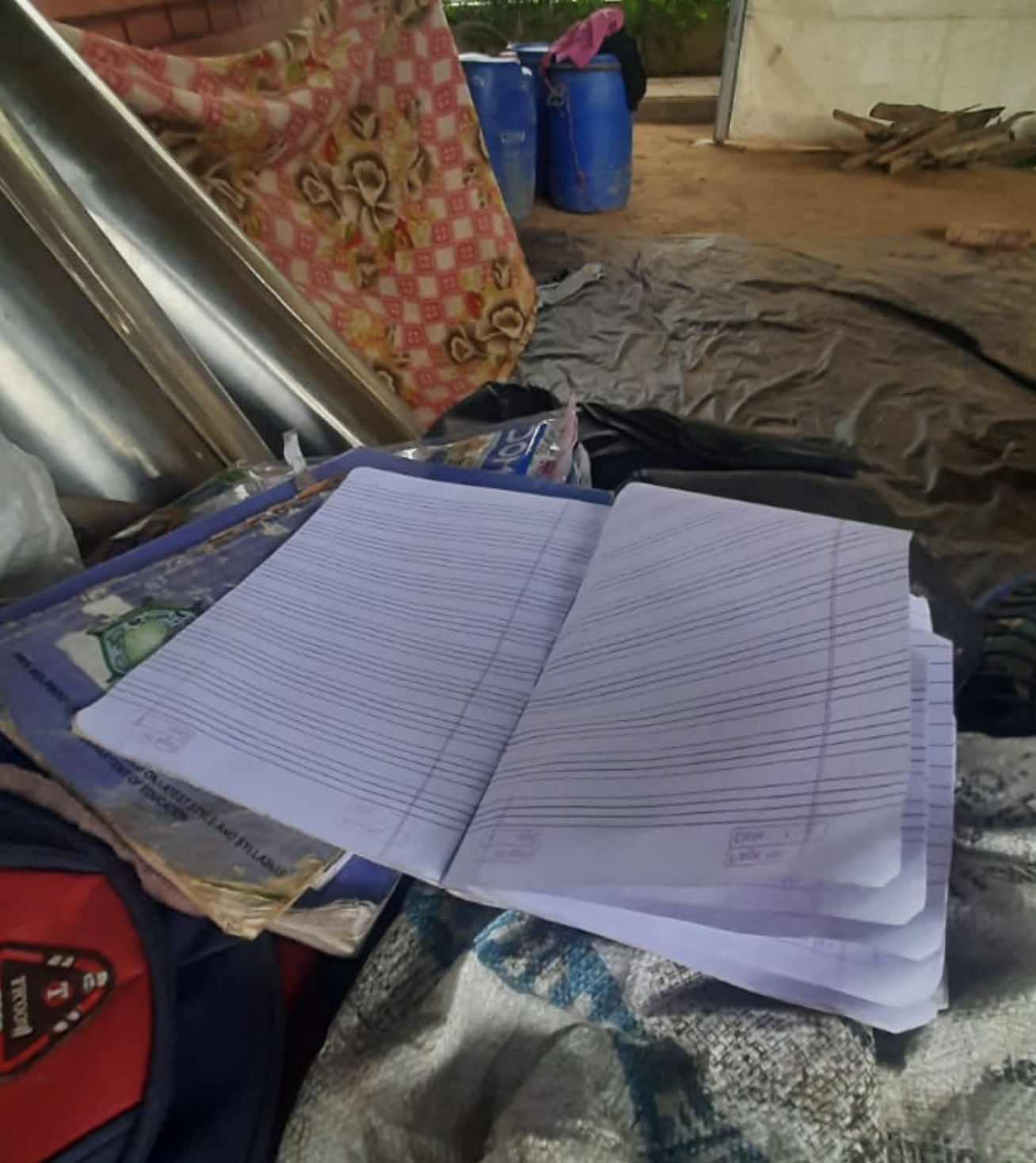 A child’s notebook in flood relief camp, a sign of hope. Despite the difficult conditions, children continue studying.