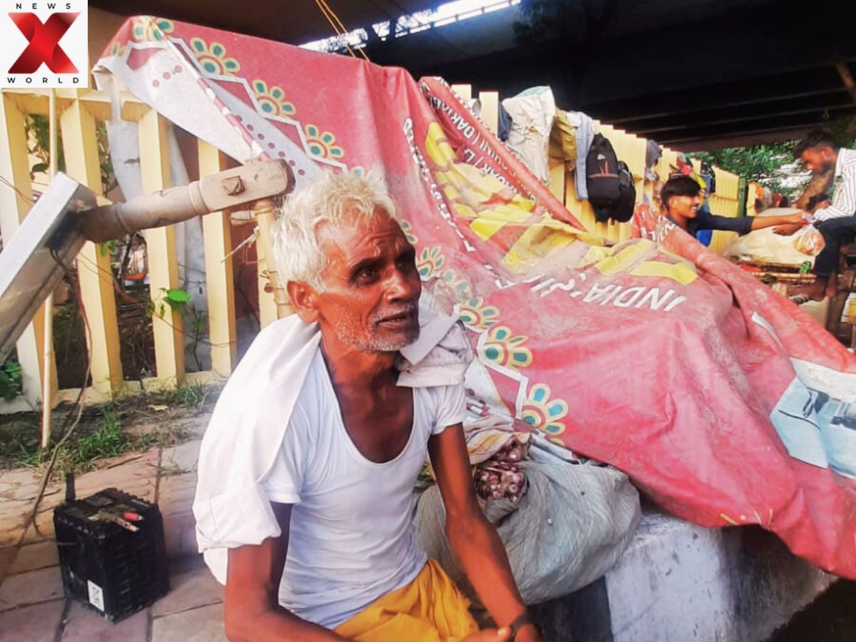 Amar Singh, displaced by the Yamuna floods, rests beside his makeshift shelter in Mayur Vihar.