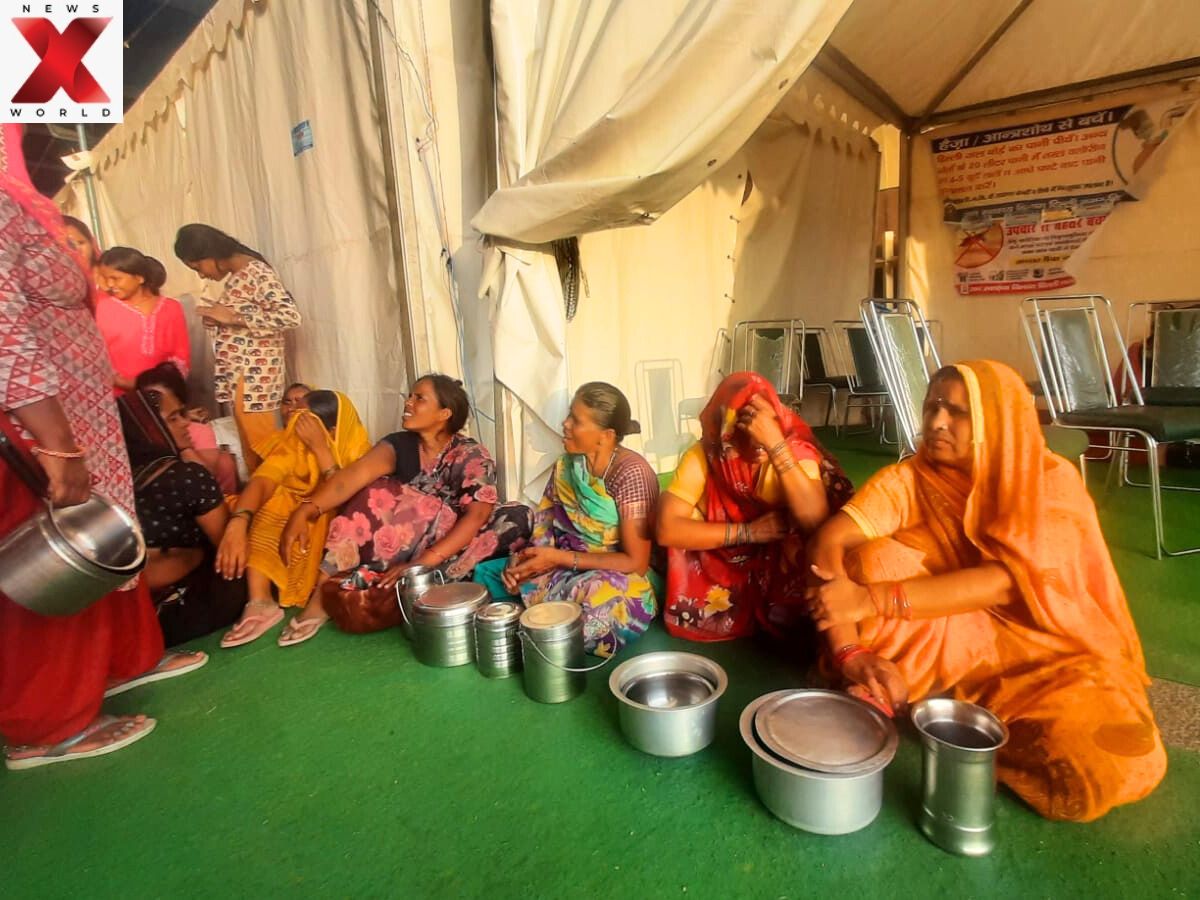 Women wait with empty vessels for food distribution at a Yamuna flood relief camp.
